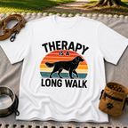 White T-shirt mockup featuring dog silhouette walking across a striped sunset beneath Therapy Is a Long Walk.