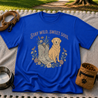 Royal T-shirt mockup featuring golden-coated dog beside floral cowboy boots and flowers beneath Stay Wild Sweet Soul.