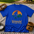 Royal T-shirt mockup featuring Bigfoot and a dog walking through pine trees beneath an orange sunset.