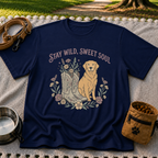Navy T-shirt mockup featuring golden-coated dog beside floral cowboy boots and flowers beneath Stay Wild Sweet Soul.